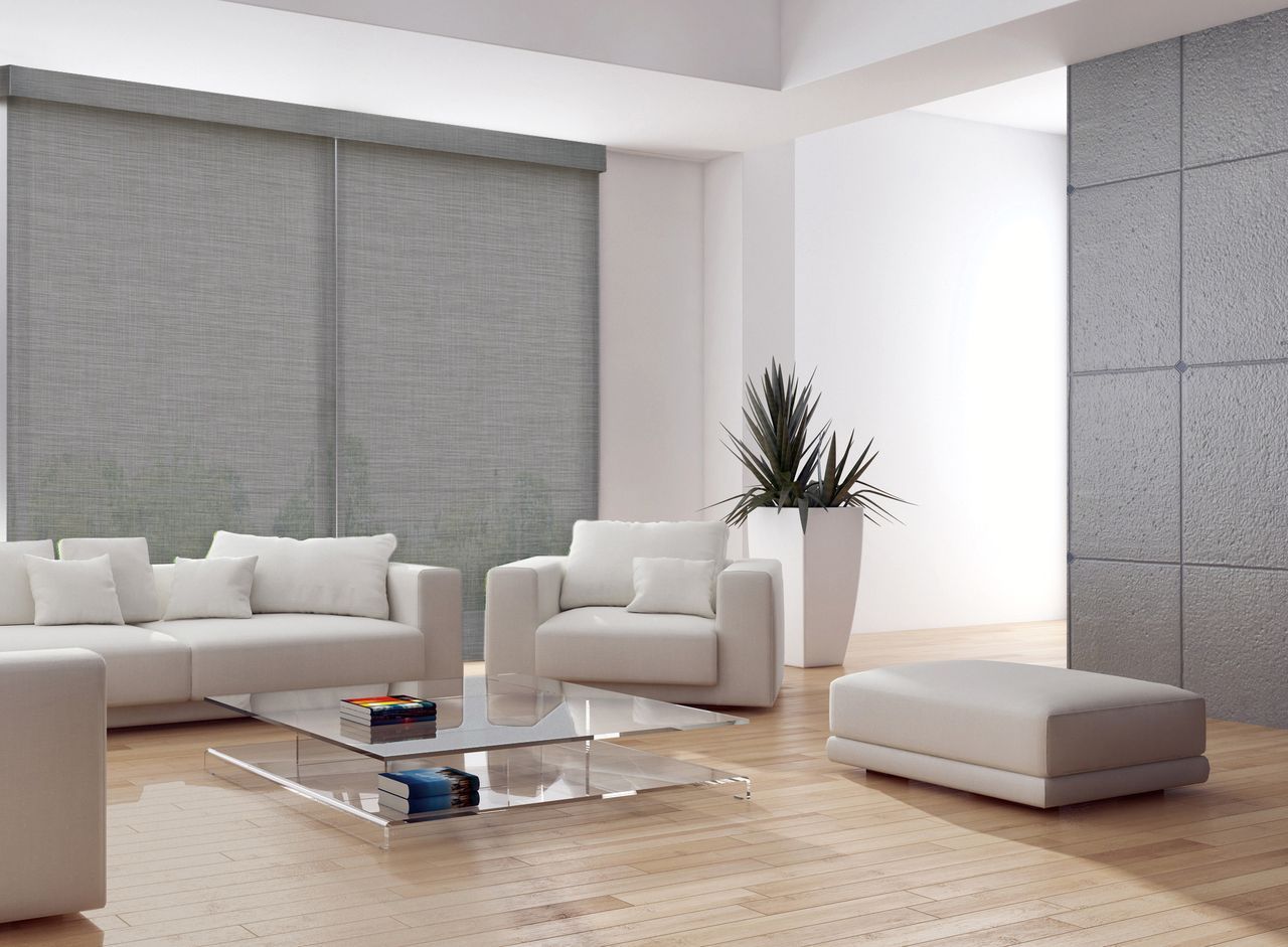 Modern living room with a white sofa, armchair, and ottoman on light wood floors, accented by gray blinds and wall panels.