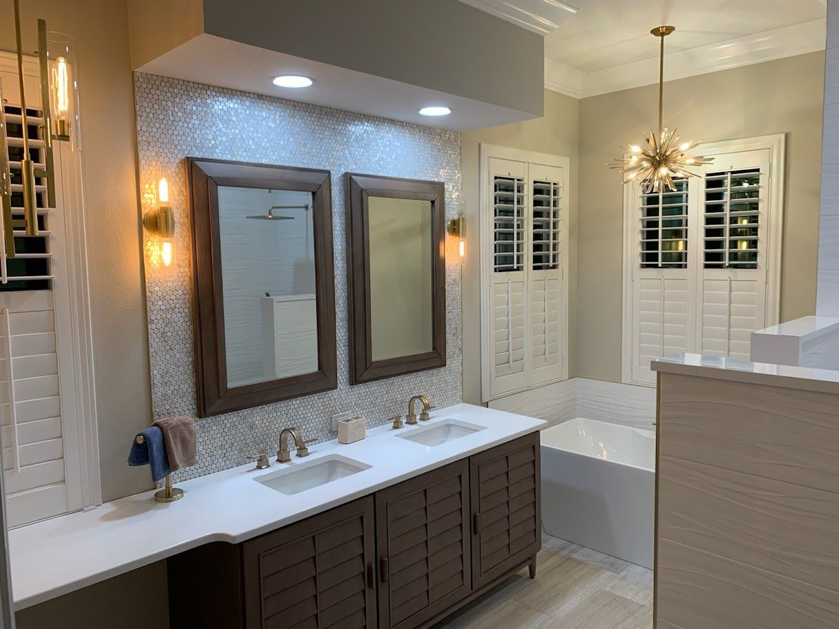 A modern bathroom with a double-sink vanity, dark wood cabinetry, a mosaic tile backsplash, mirrors, and a soaking tub.