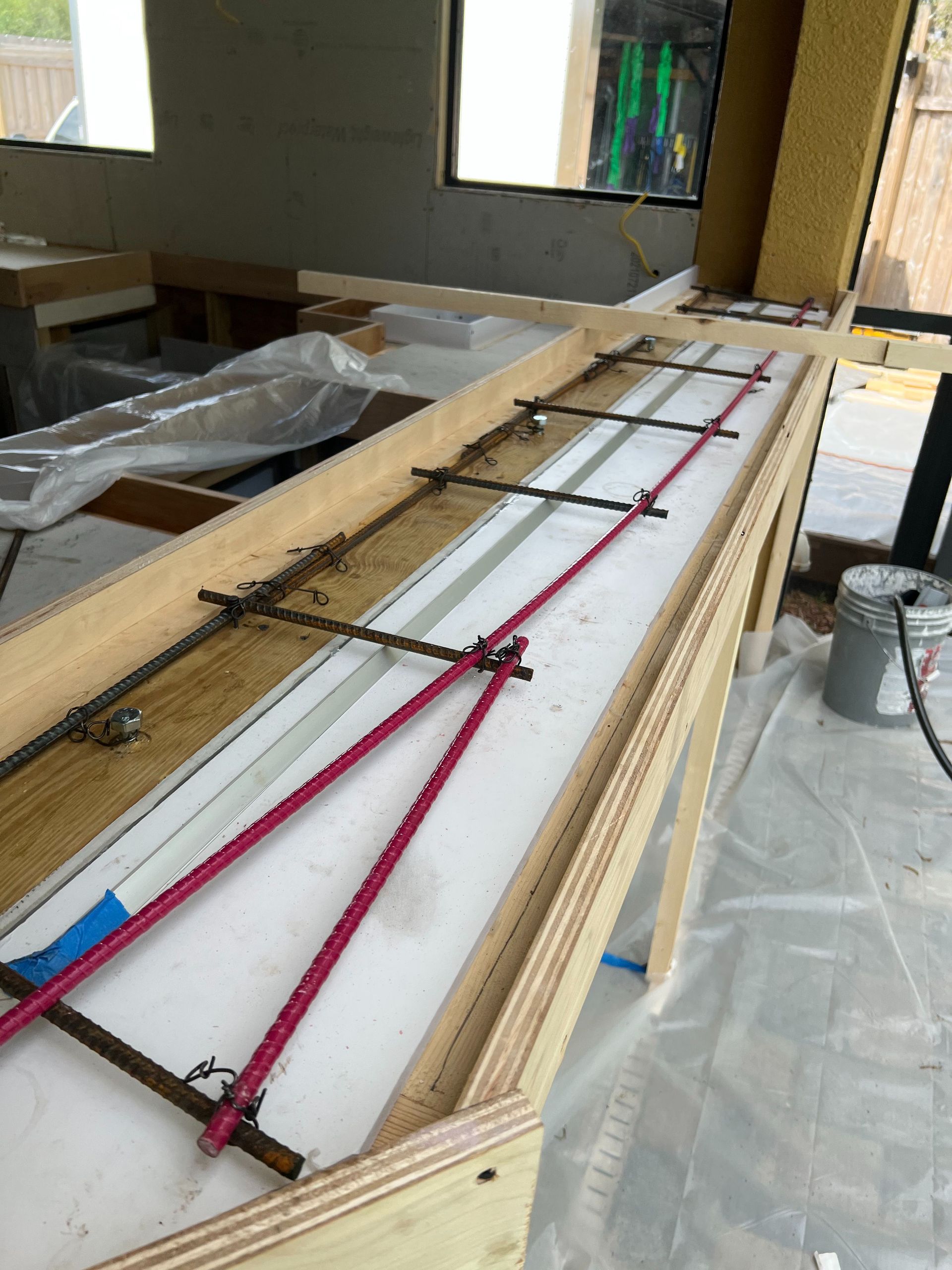 A wooden formwork frame on a construction site contains steel rebar arranged for a concrete pour.