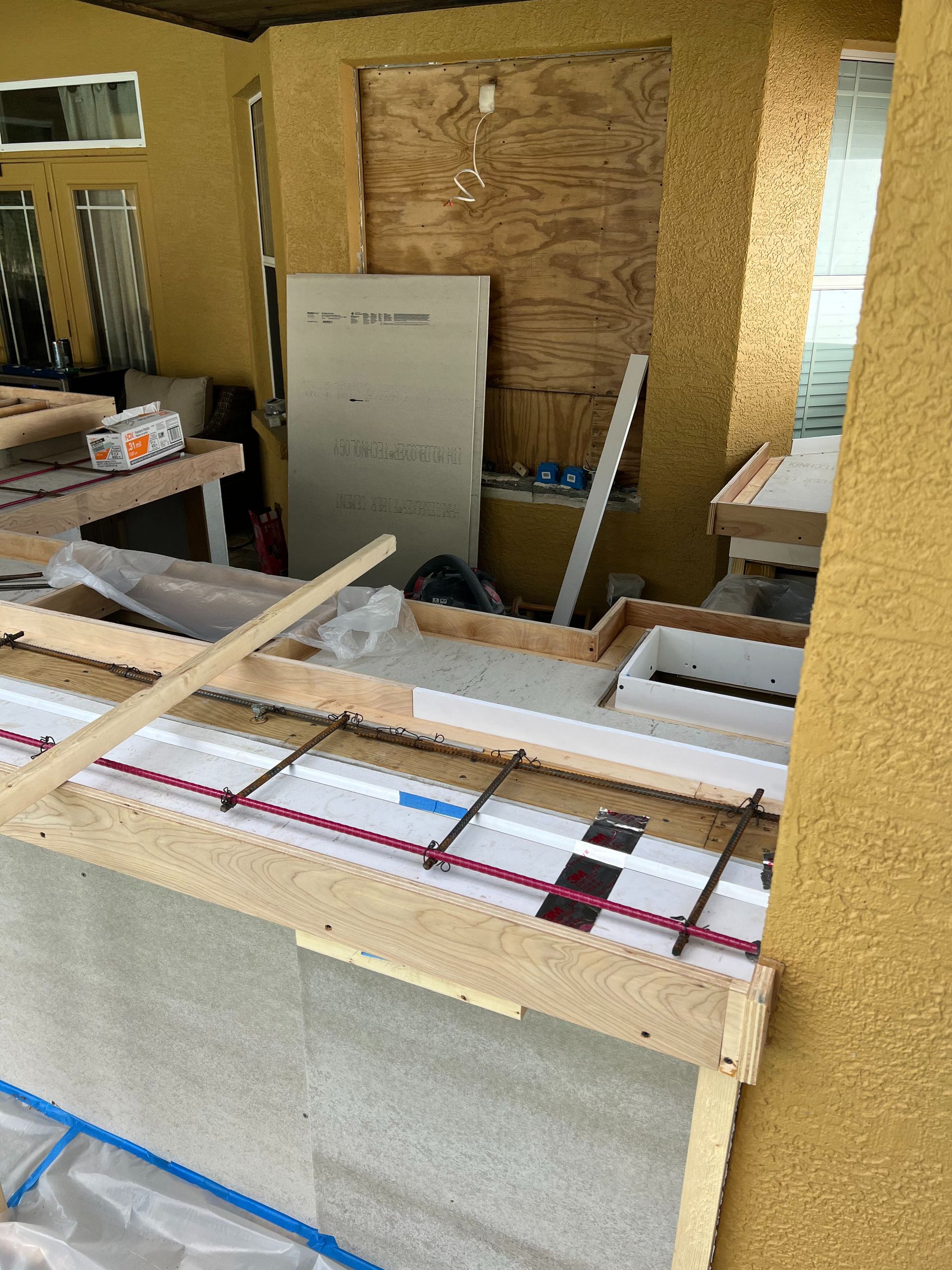 An outdoor kitchen counter under construction with a wooden form, metal rebar, and foam insulation boards.