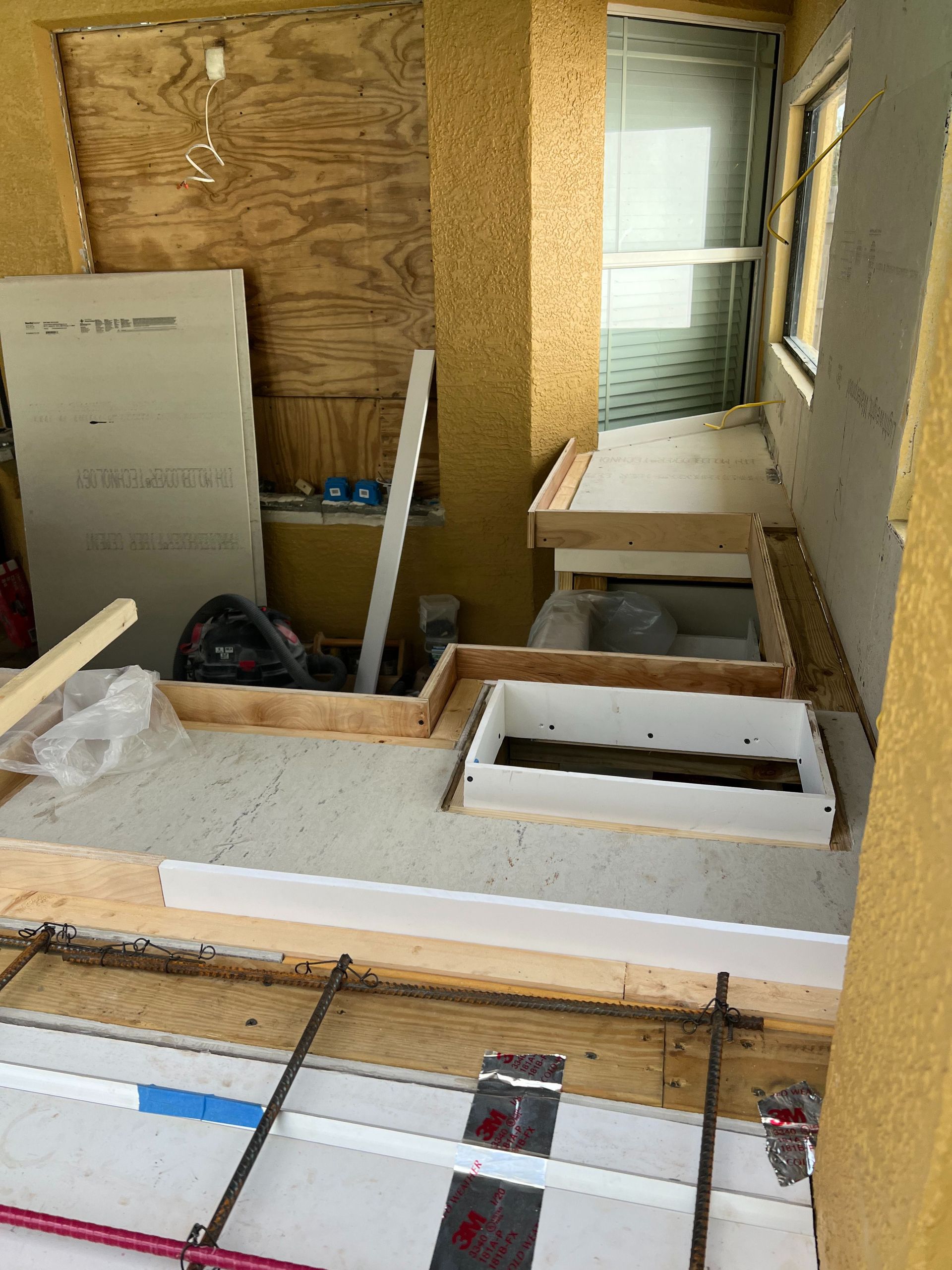 Construction site showing a framed step and a shower base tray installed on a subfloor.