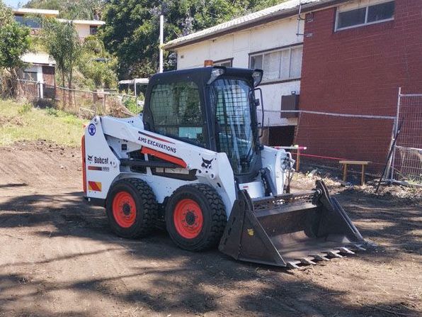 A bobcat skid steer is parked in front of a brick building
