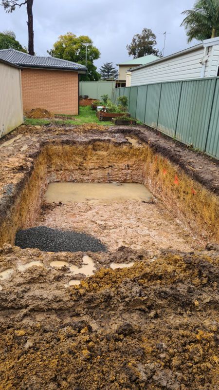 A swimming pool is being built in the backyard of a house.