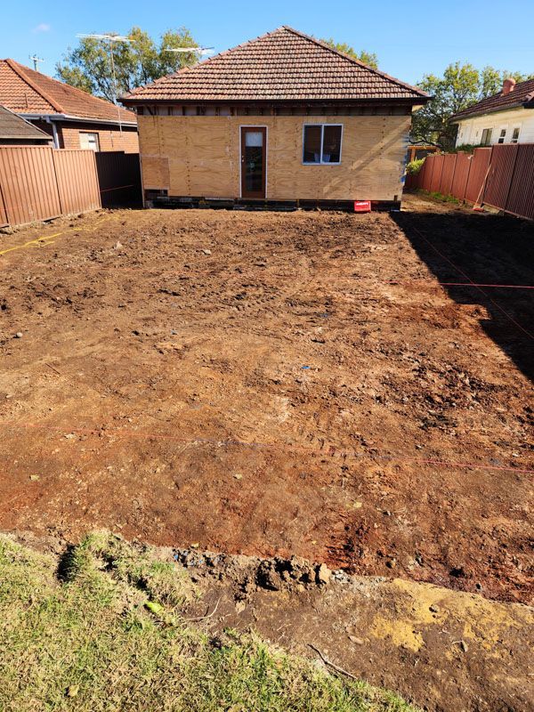 A house is sitting in the middle of a dirt field.