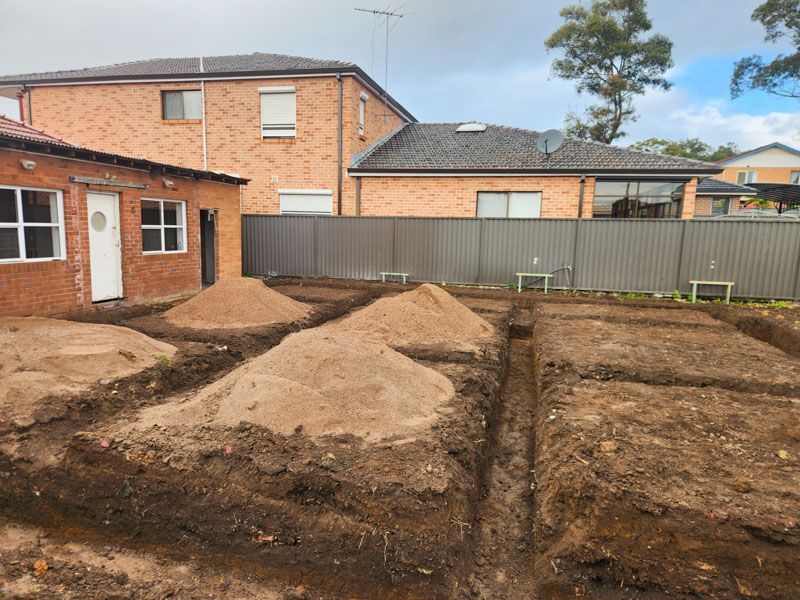 A pile of dirt is sitting in front of a brick house.