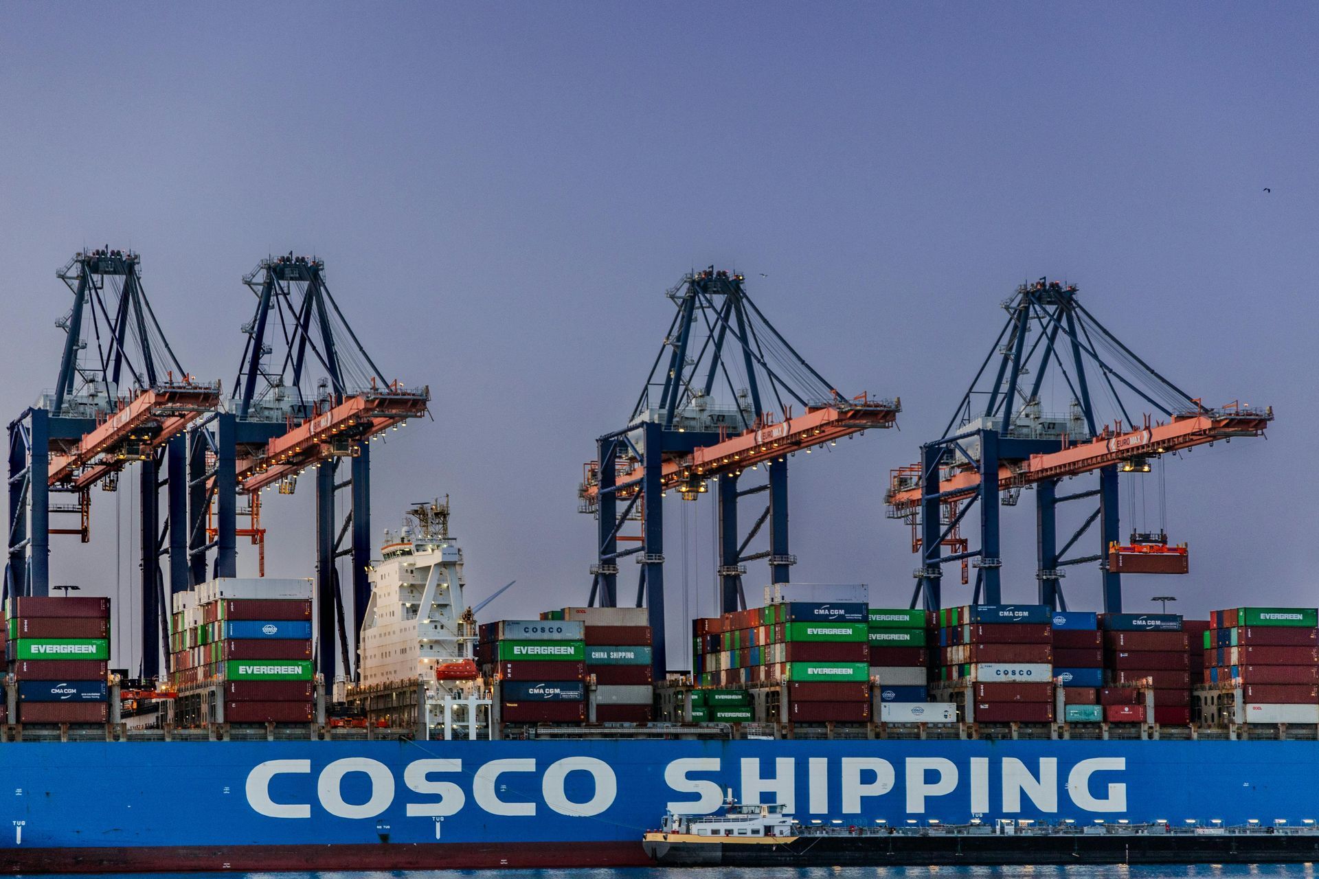 Containerkranen boven een vrachtschip van COSCO Shipping in een haven.