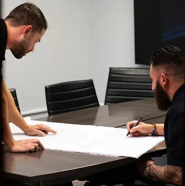 Two men are sitting at a table writing on a piece of paper