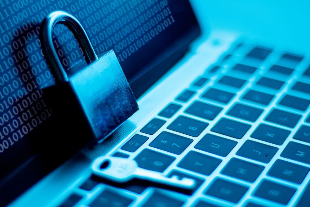 An image of a blue-tinted laptop with a padlock and key resting on it