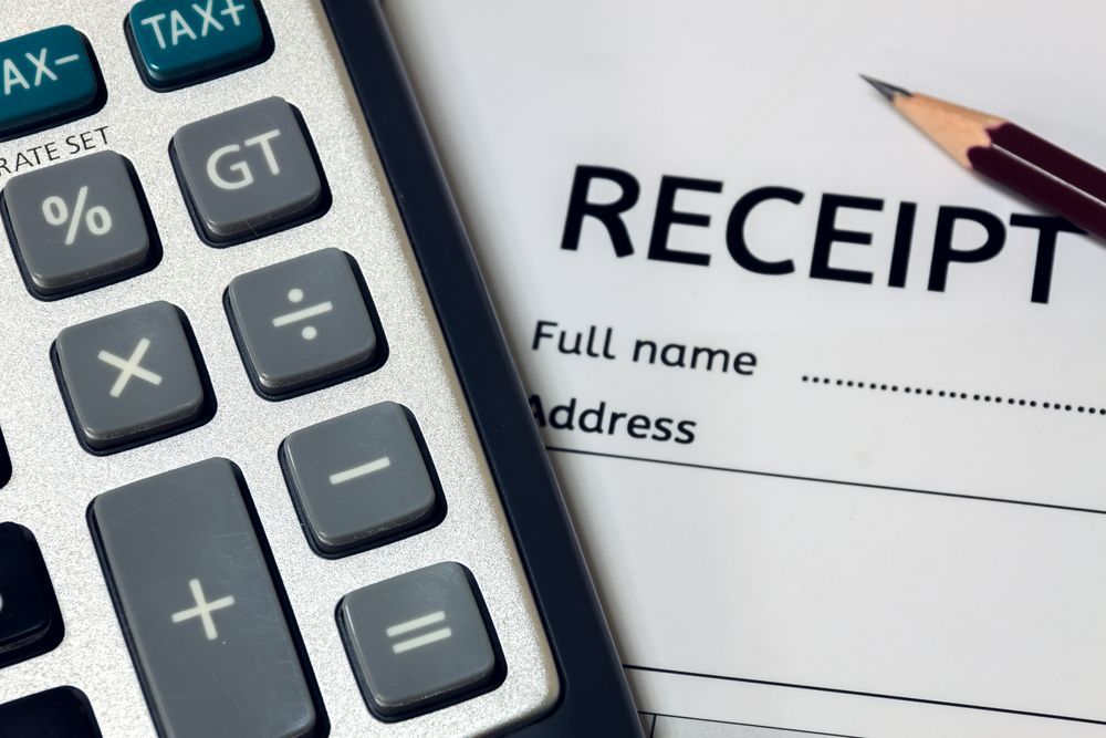 An image of a calculator and pencil resting on top of a paper receipt