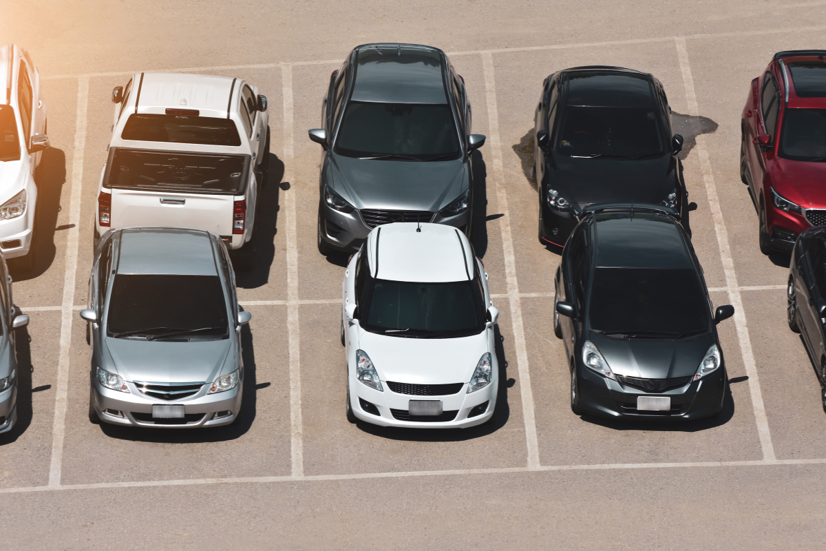 Overhead view of several parked cars in marked parking spaces on a lot