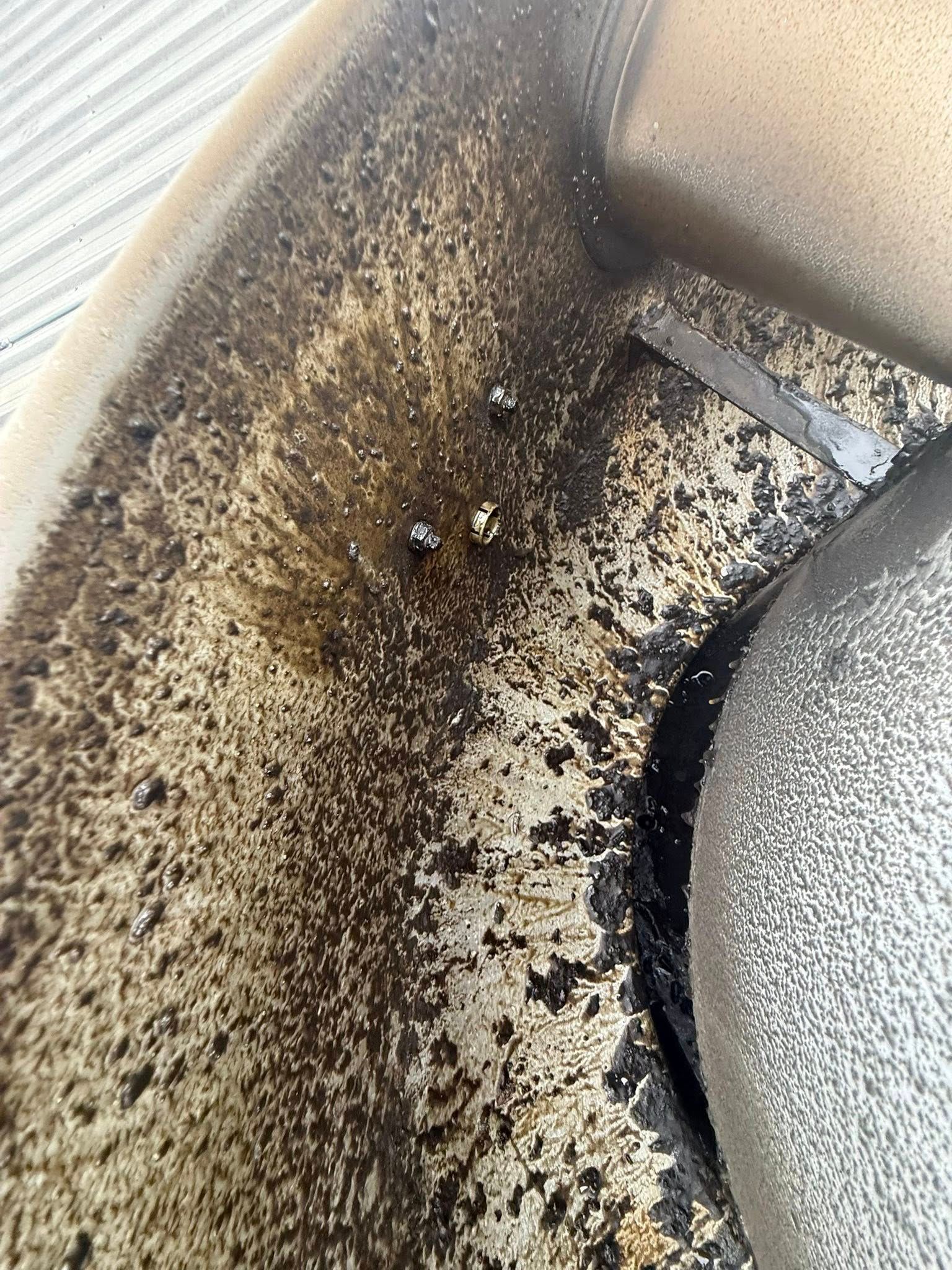 Dirty car seat with scattered crumbs and dark stains, showing heavy wear and grime