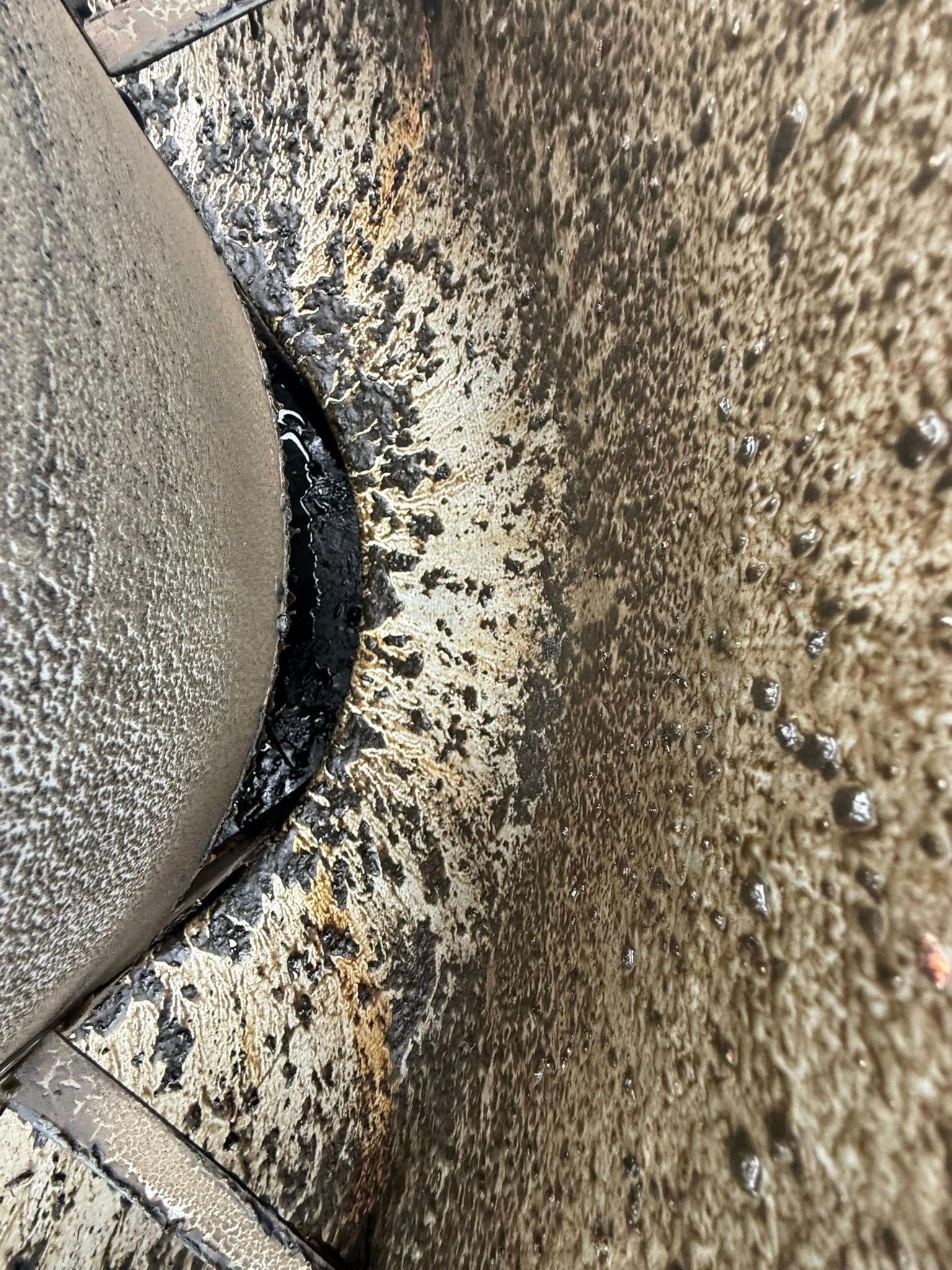 Close-up of a dirty concrete surface with black grime and a beige stone edge