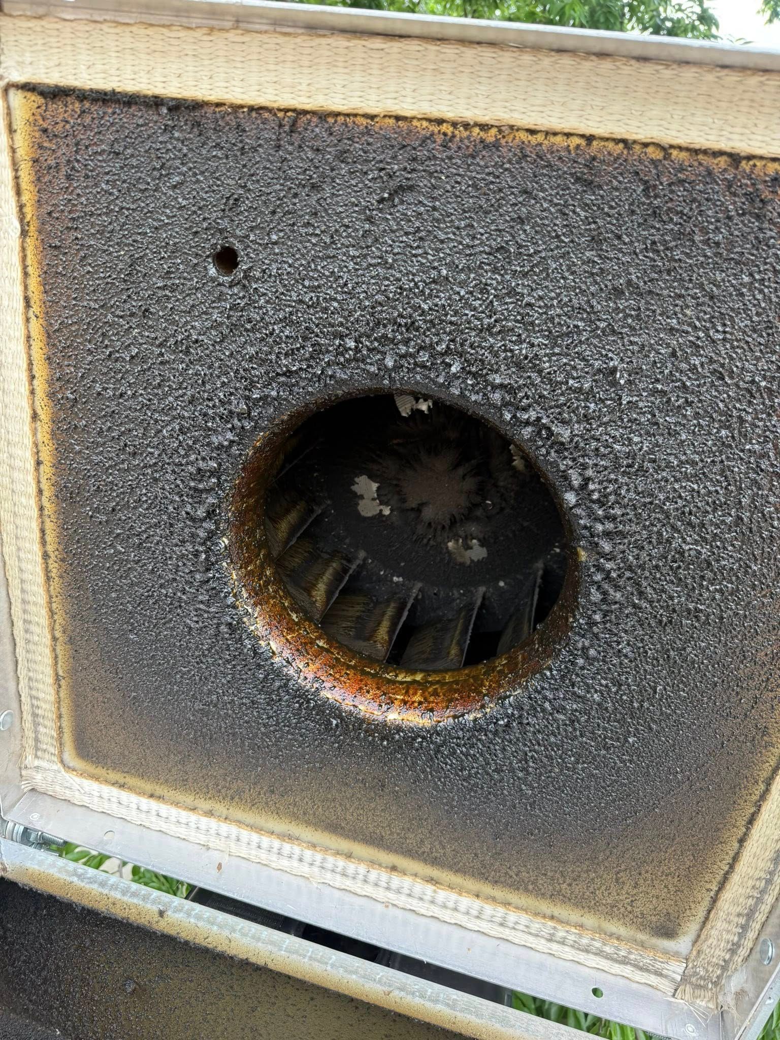 Close-up of a weathered metal speaker box with a central round opening and rusted edges