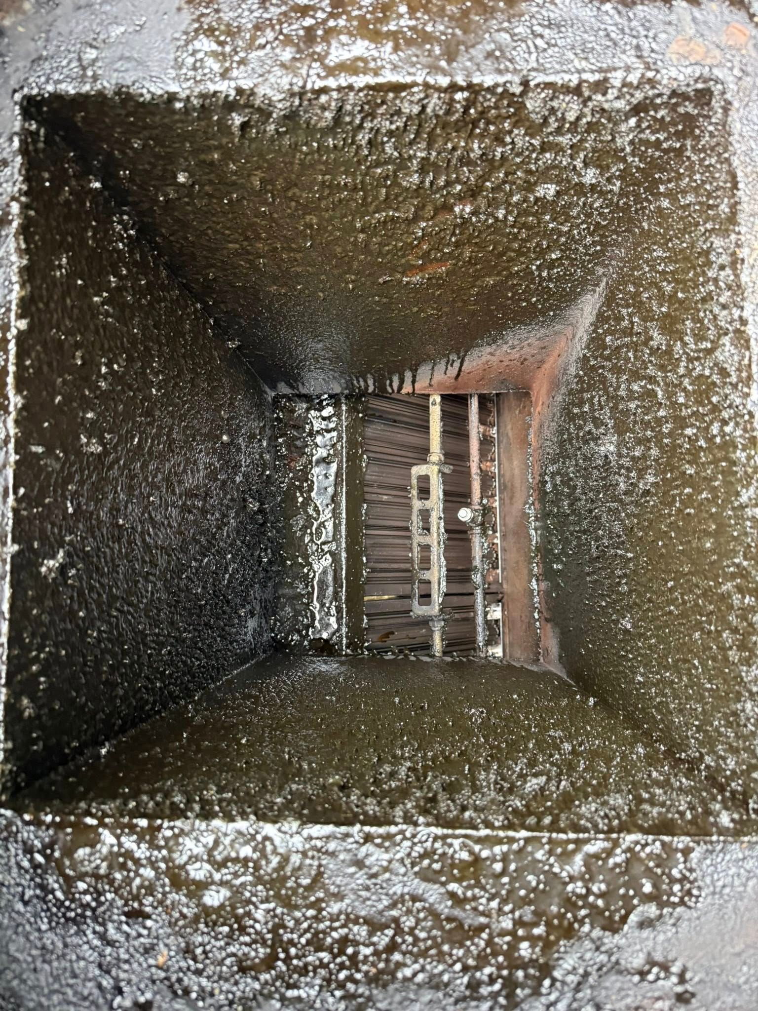 Dusty square vent or duct opening with a ladder visible at the far end and light coming in from the right.