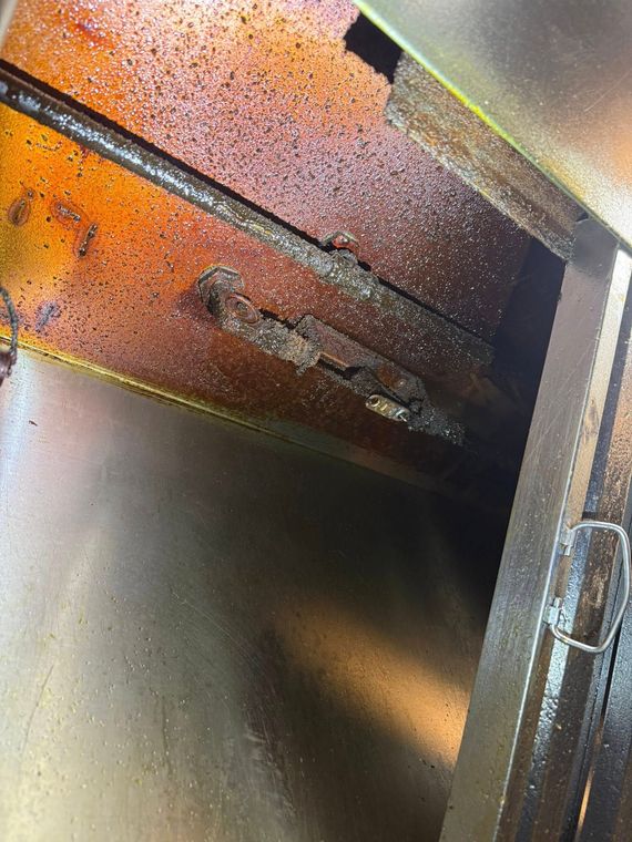A close-up of a rusty metal interior with a diagonal beam and dark opening.