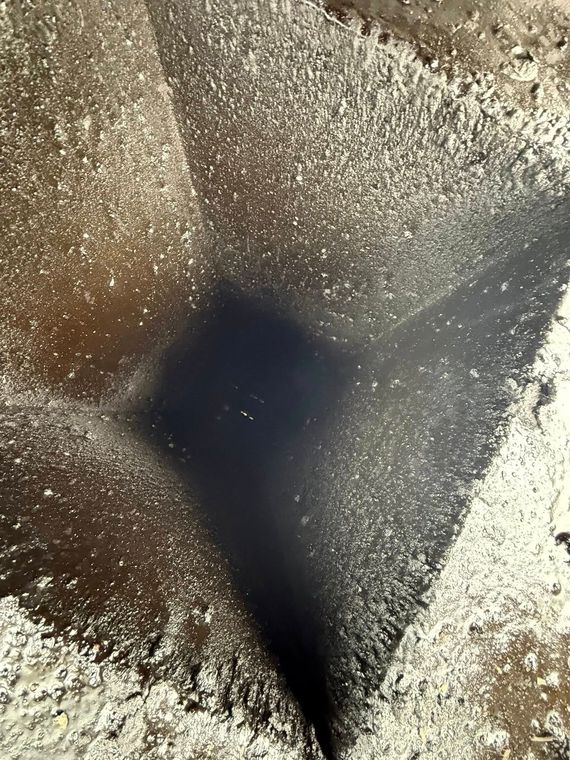 Close-up of a dark, textured funnel or drain opening surrounded by speckled brown and white material