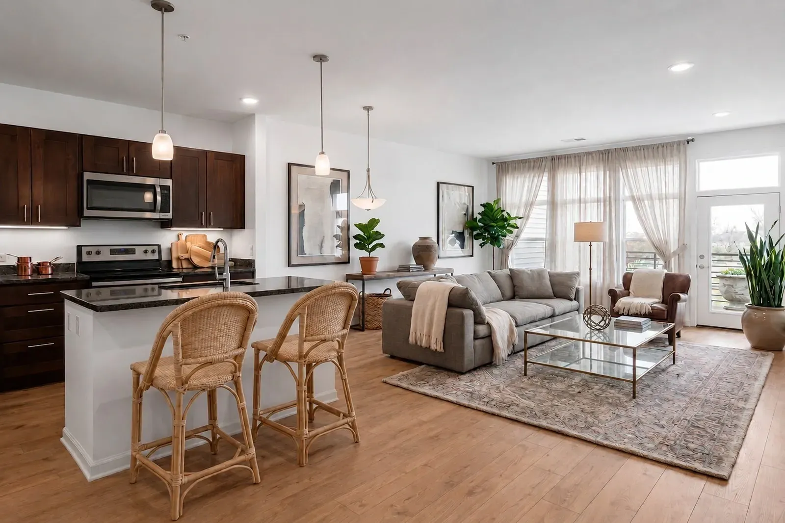 Modern kitchen and living room area with island, bar stools, sectional sofa, and coffee table.