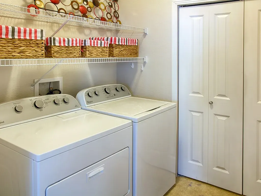 In-unit washer and dryer with storage baskets above.