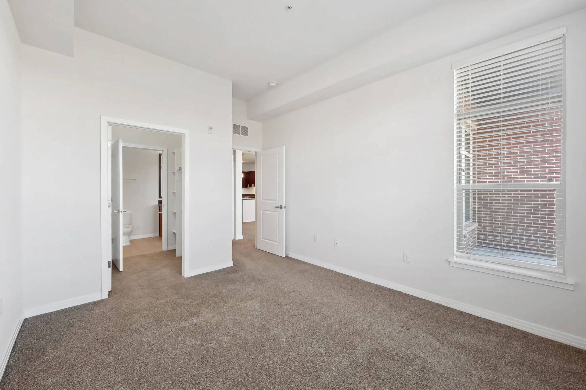 Bedroom with doorway to bathroom and view of kitchen.