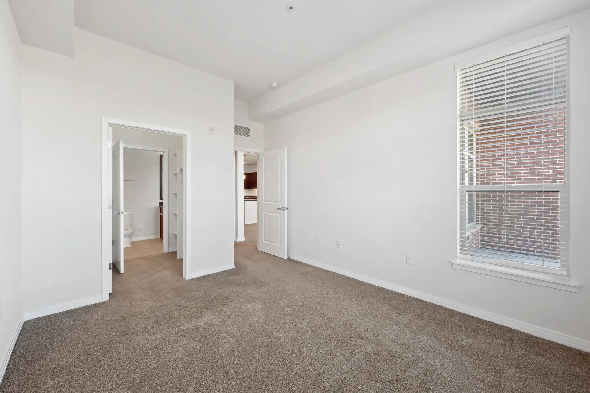 Bedroom with doorway to bathroom and view of kitchen.