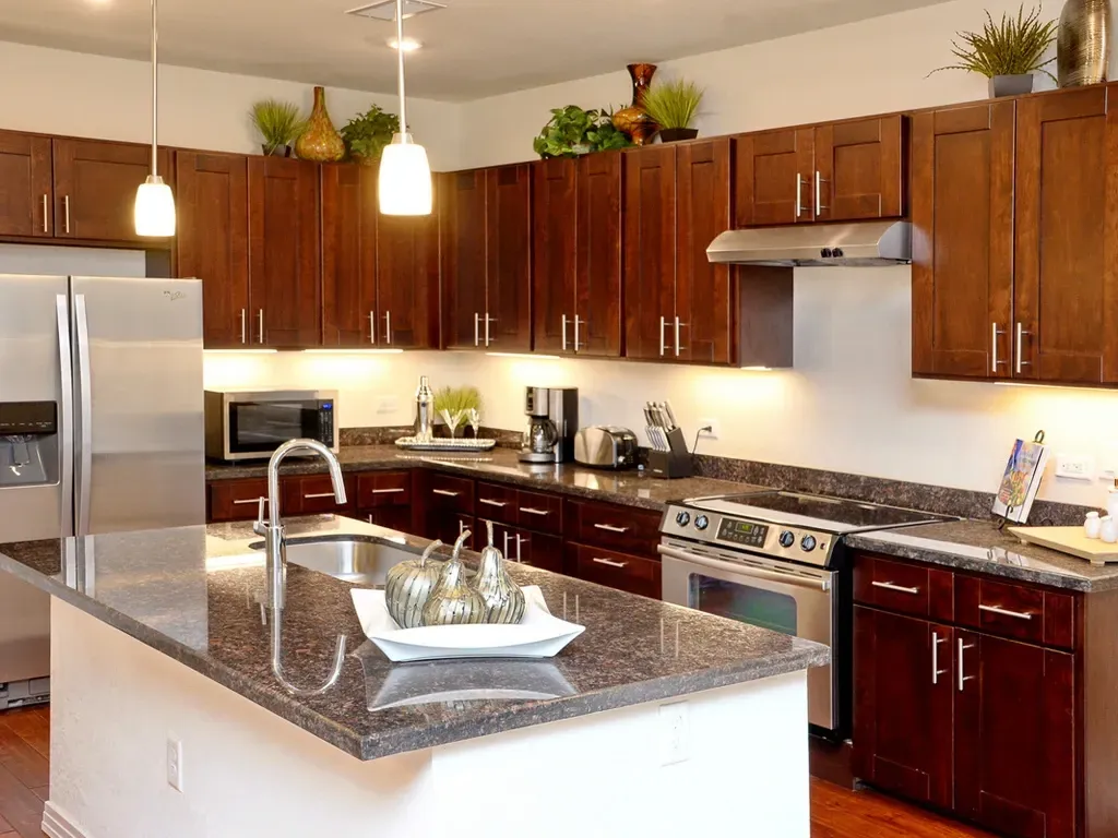 Modern kitchen with dark wood cabinets, granite countertops, and stainless steel appliances.