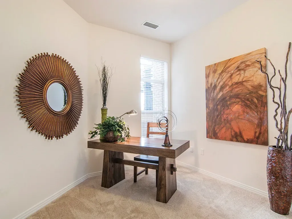 Bright minimalist room with a rustic wooden table, wall art, and a potted plant by a window.