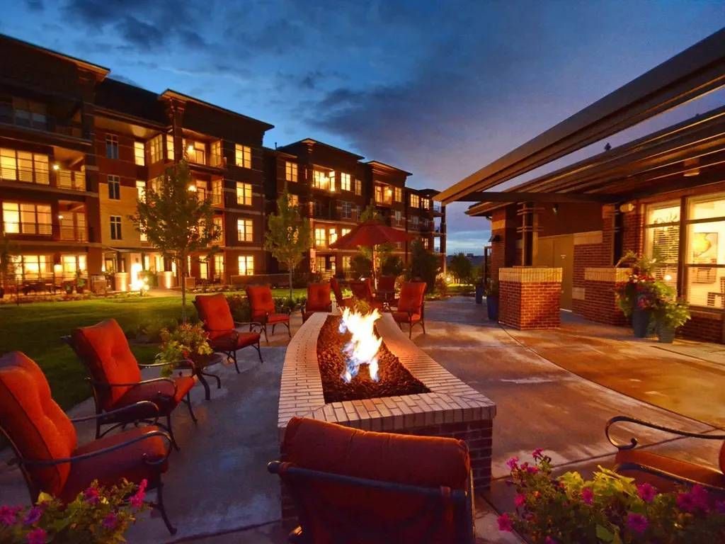 Courtyard fire pit with red chairs at a modern apartment complex at dusk.