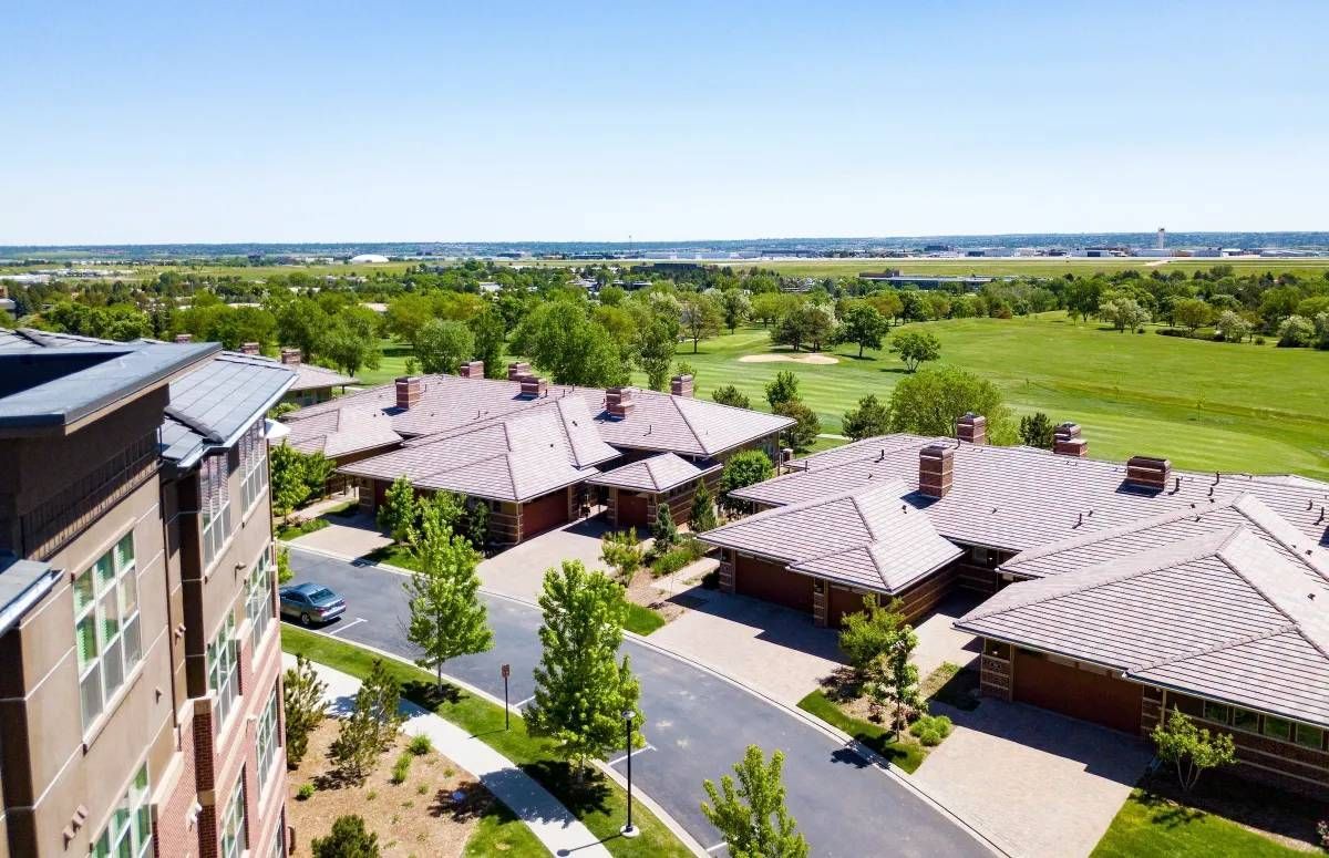 Aerial view of modern apartment buildings beside green fields under a clear sky.
