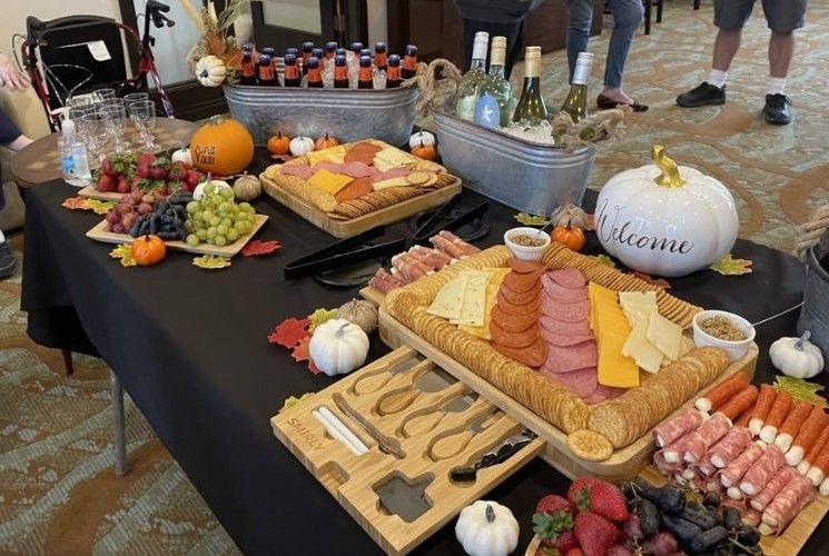 Fall charcuterie table with meats, cheese, fruit, pumpkins, and a “Welcome” pumpkin centerpiece.