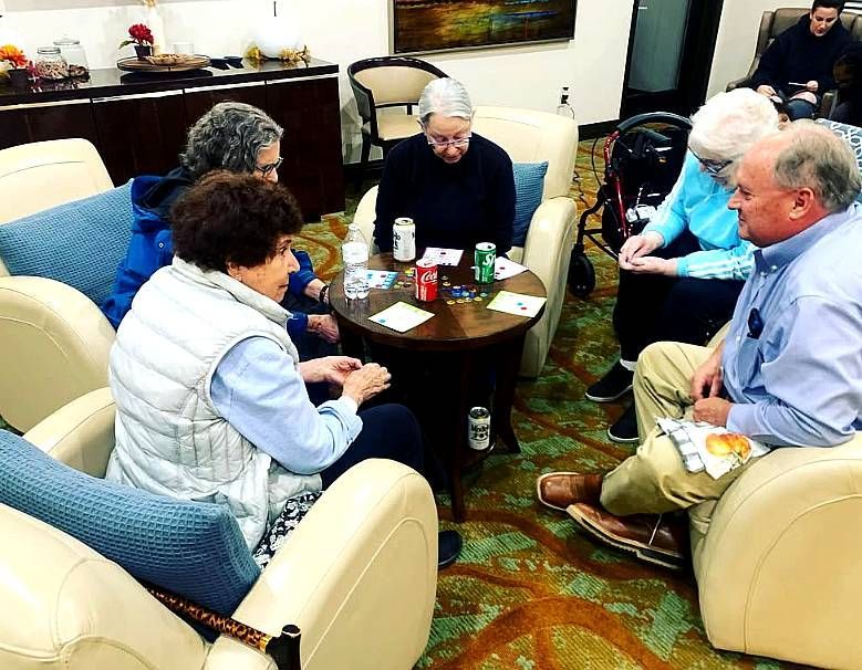 People seated in a circle talking in a cozy lounge with chairs and a small table.
