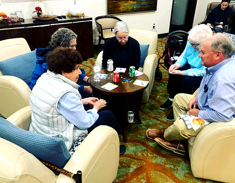 People seated in a circle talking in a cozy lounge with chairs and a small table.