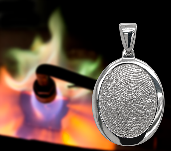 Silver oval pendant with textured center in front of a colorful flame