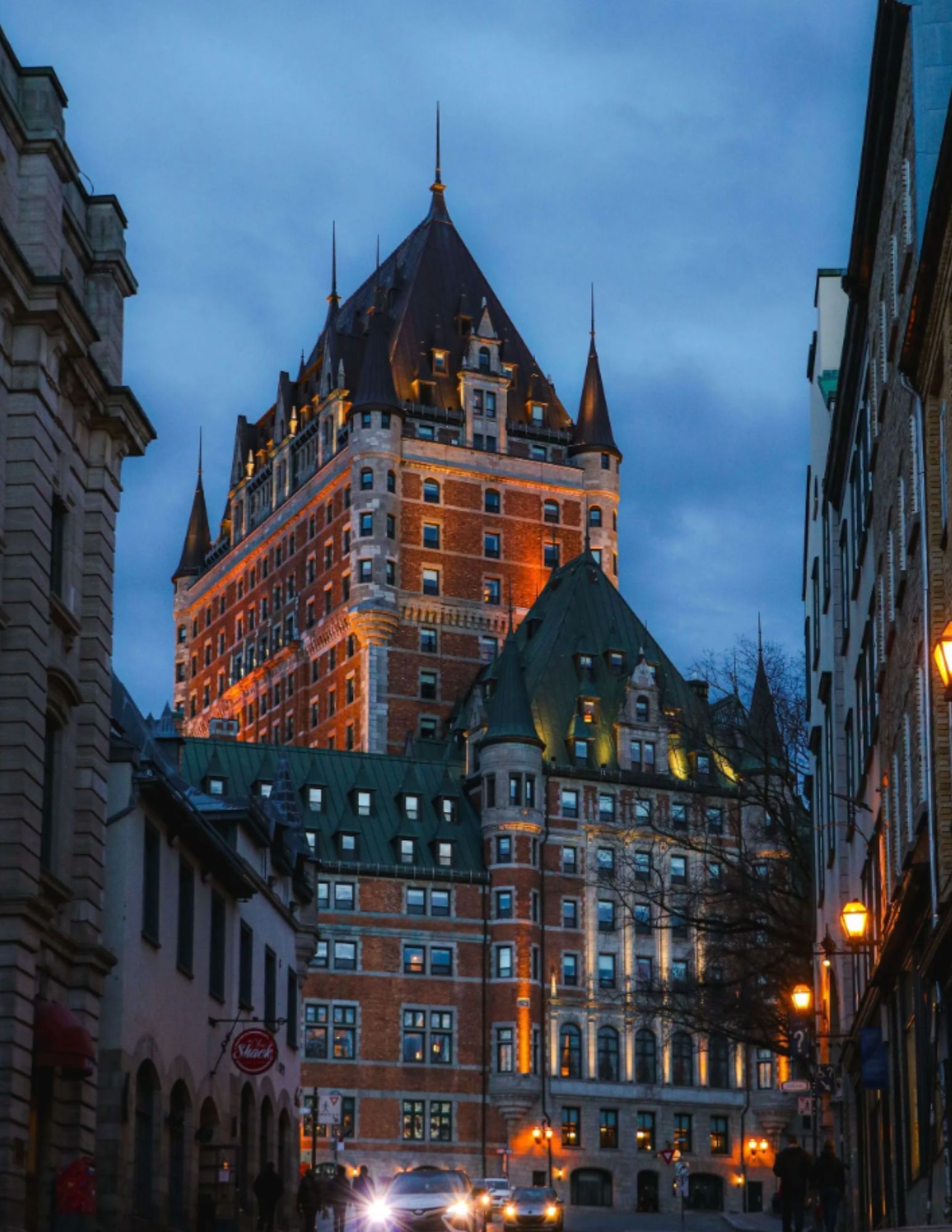 Illuminated Fairmont Le Château Frontenac rising above a historic Old Québec street at dusk.