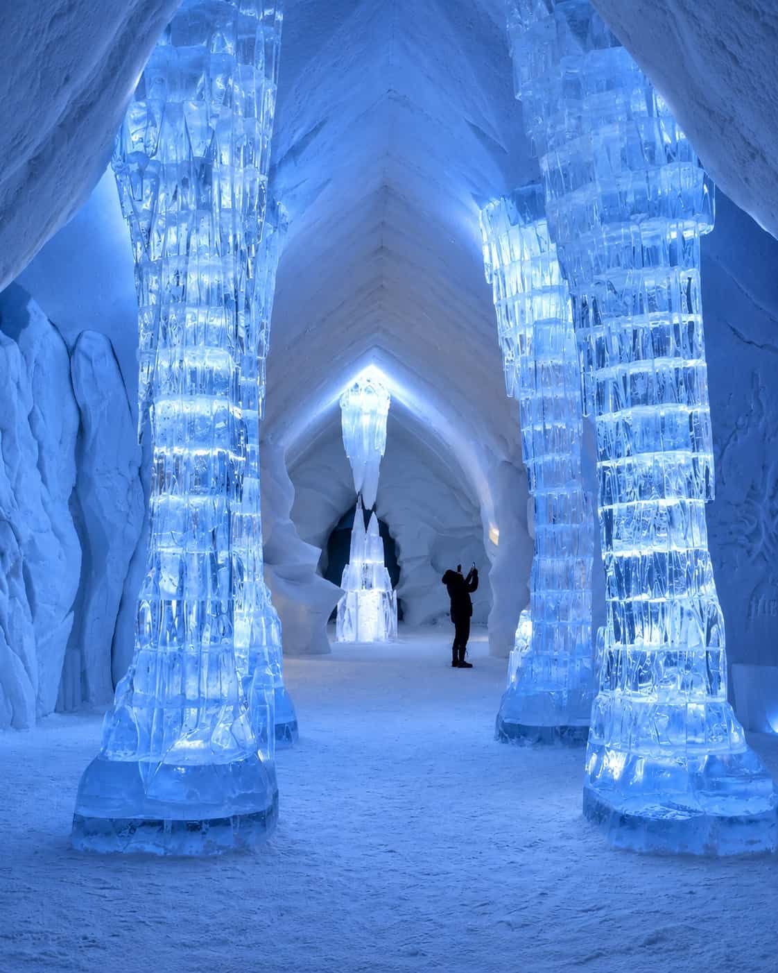 Blue-lit ice columns and sculpted snow arches inside Hôtel de Glace near Québec City`