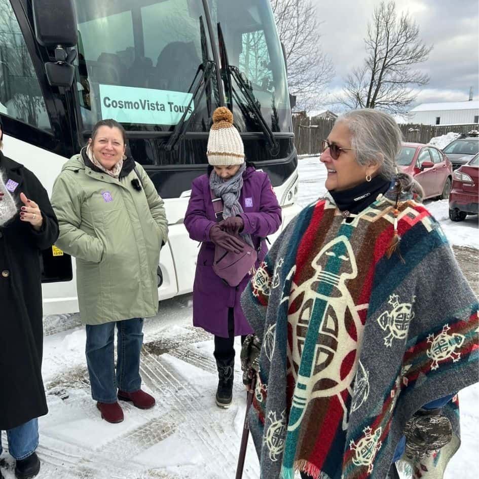 Indigenous cultural guide welcoming CosmoVista Tours guests beside their coach in Québec City