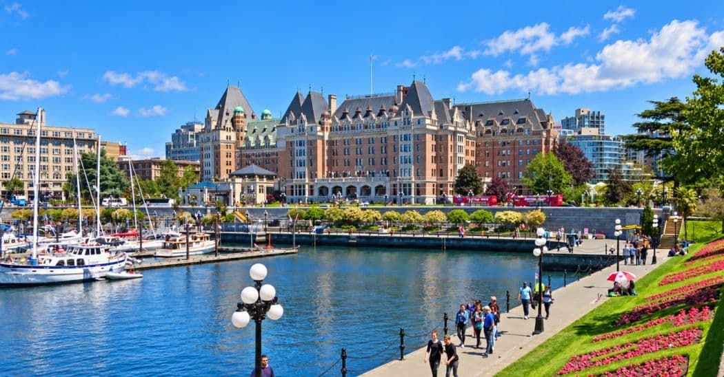 Victoria Inner Harbour with colourful flowers, boats and waterfront buildings under a blue sky.