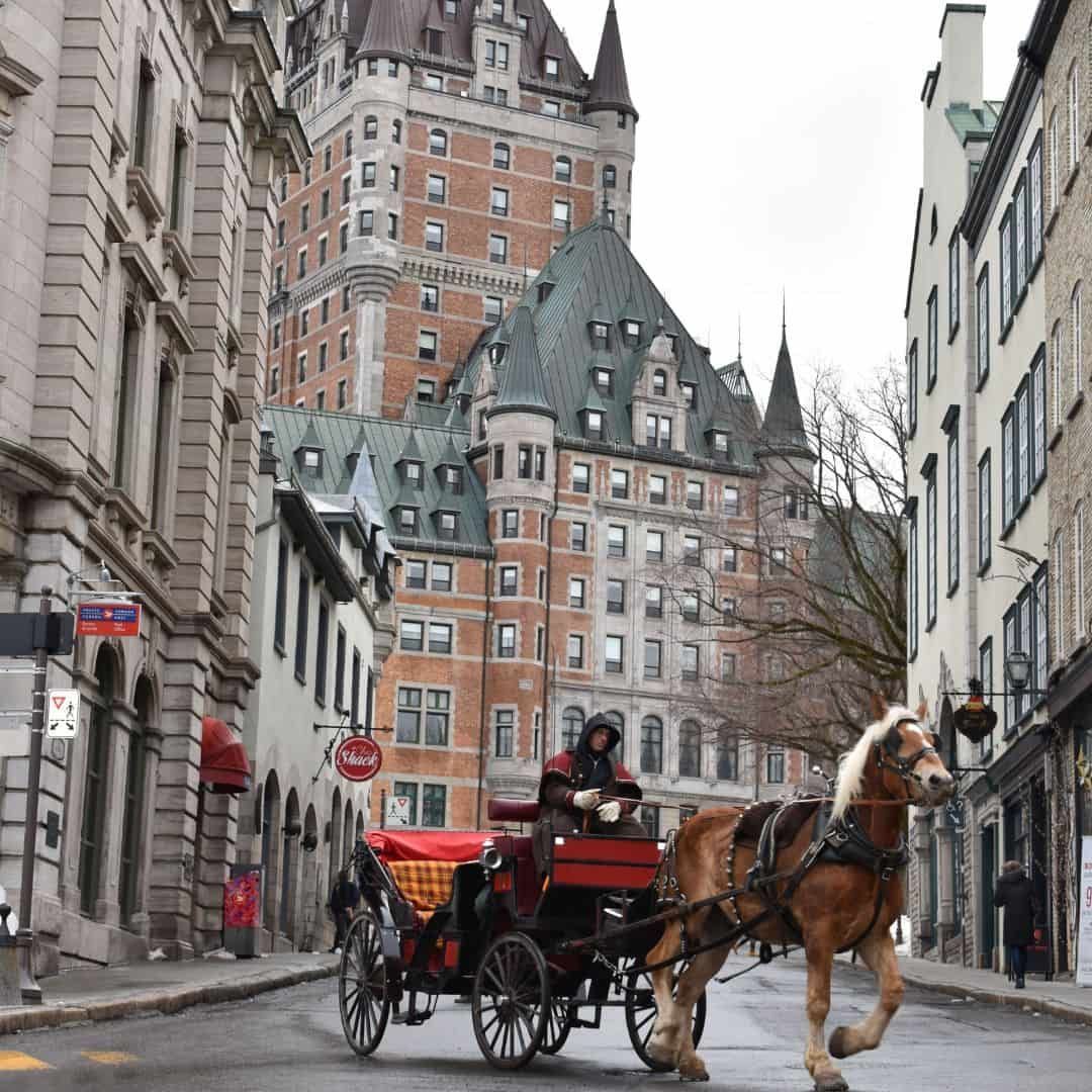 Illuminated Fairmont Le Château Frontenac rising above a historic Old Québec street at dusk.
