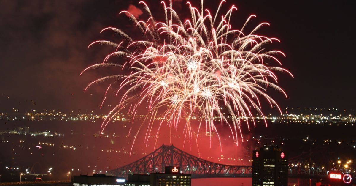Red and white fireworks illuminate the night sky above Montréal’s Jacques Cartier Bridge and city skyline.
