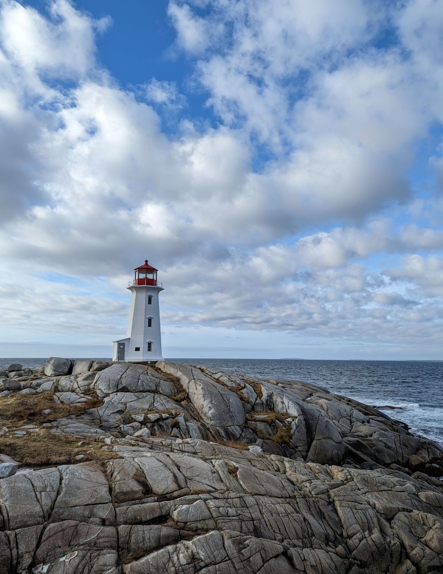 Peggy's Cove Lighthouse in Nova Scotia, Canada, surrounded by rugged granite coastline and Atlantic Ocean views, a highlight of the CosmoVista Tours Atlantic Canada Coastal Masterpiece tour.
