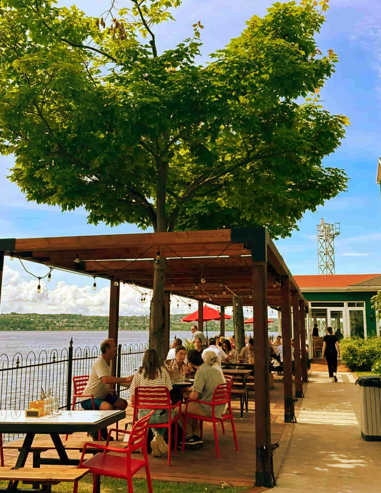 Guests enjoying lunch on the waterfront terrace at Auberge La Goéliche on Île d'Orléans, overlooking the St. Lawrence River near Québec City.