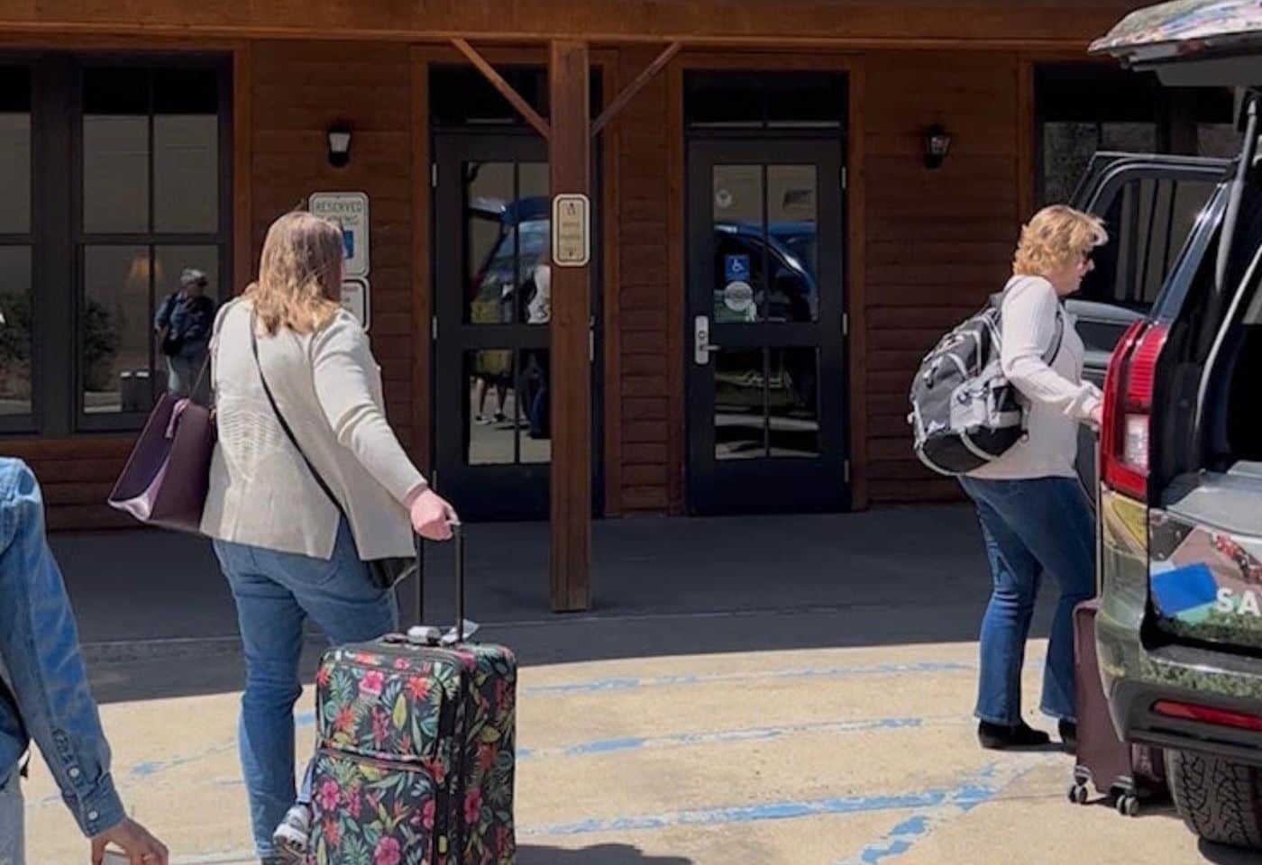 Group oftravelers with rolling suitcases boarding a tour bus 