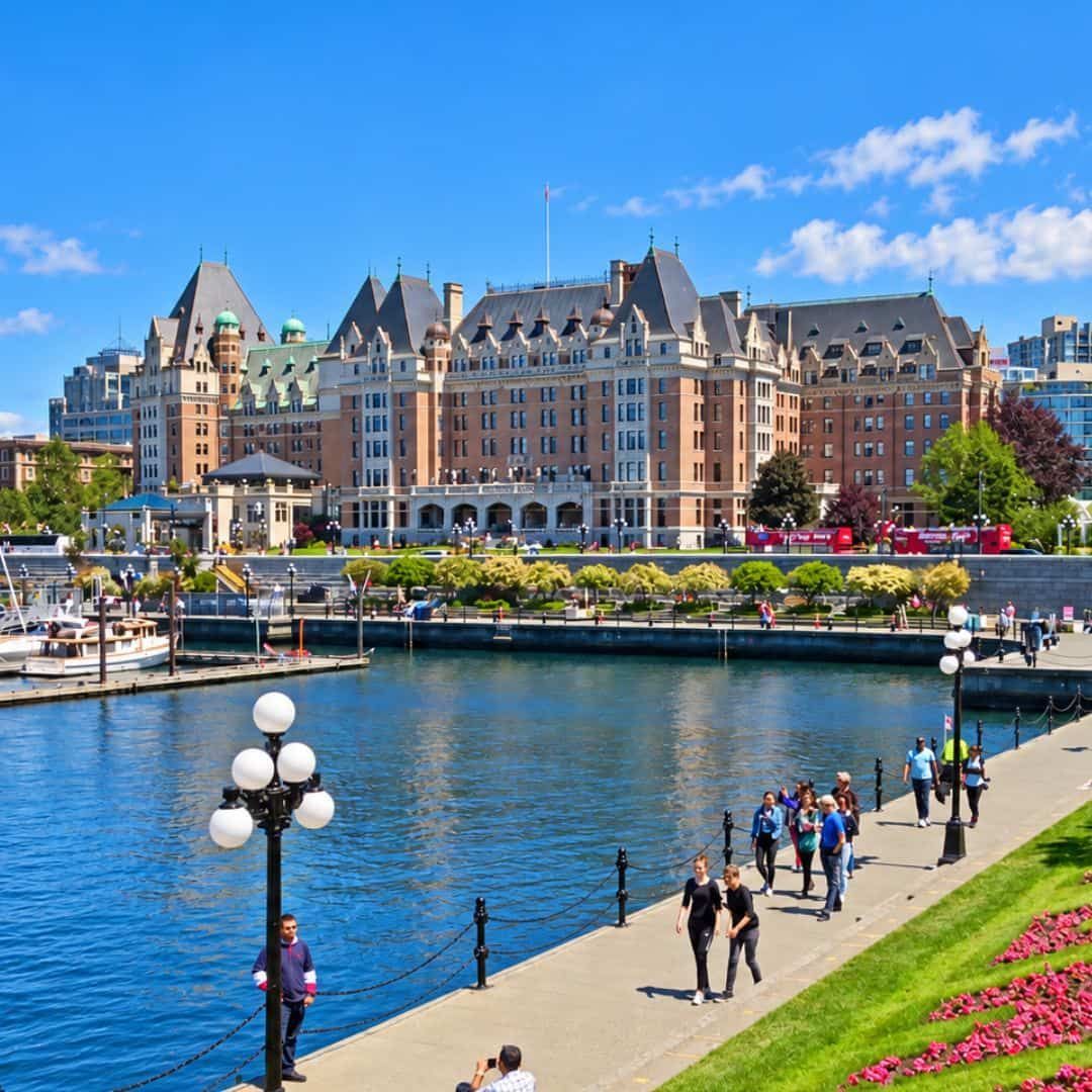 Victoria Inner Harbour with colourful flowers, boats and waterfront buildings under a blue sky.