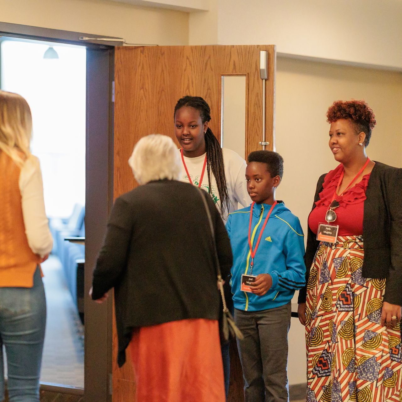A group of people are standing in front of a door talking to each other at North Park Church