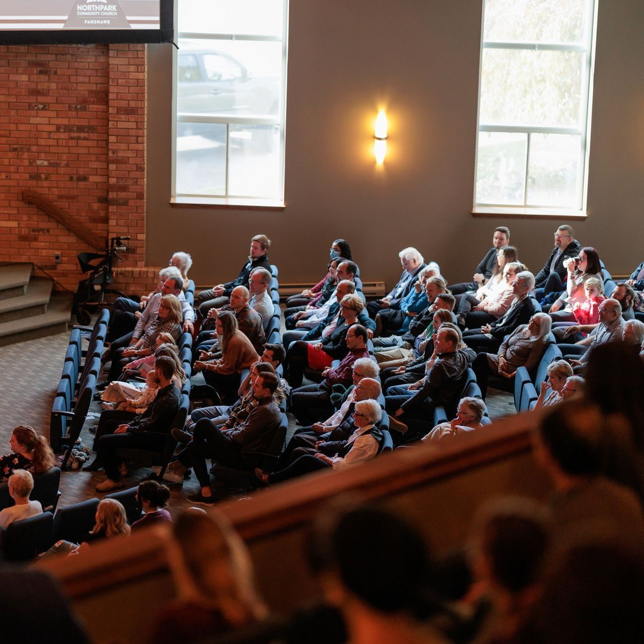 A large group of people are sitting in an auditorium watching a presentation