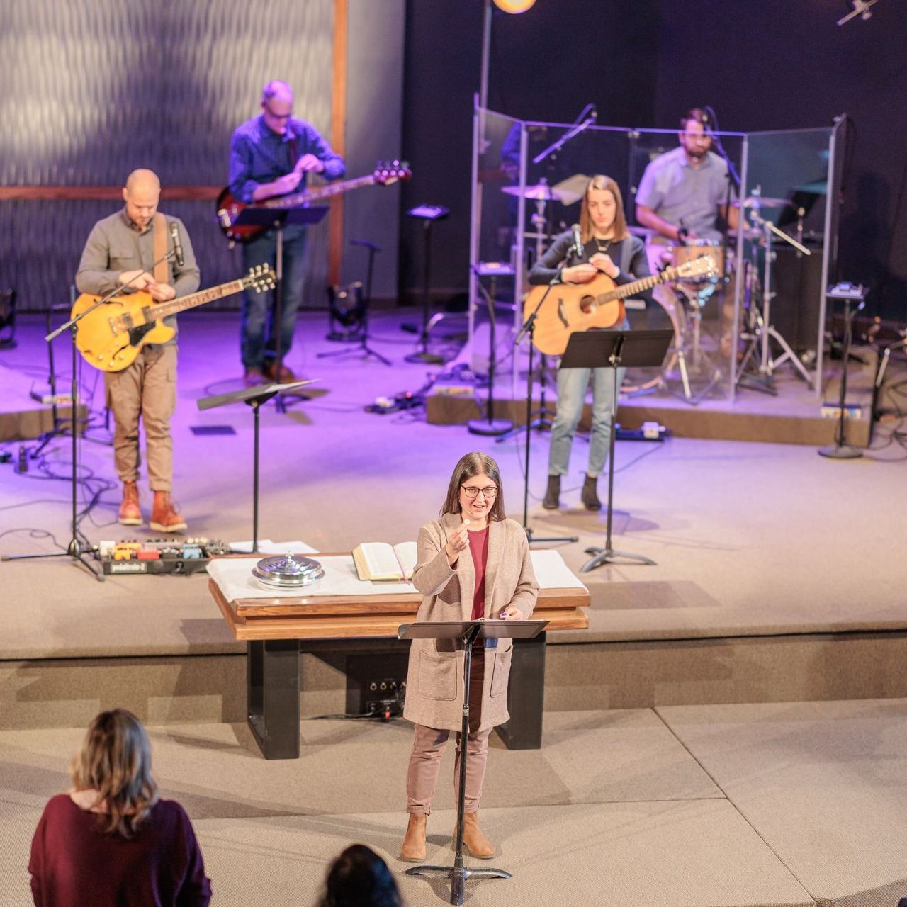 A group of people playing instruments on a stage including a woman singing into a microphone