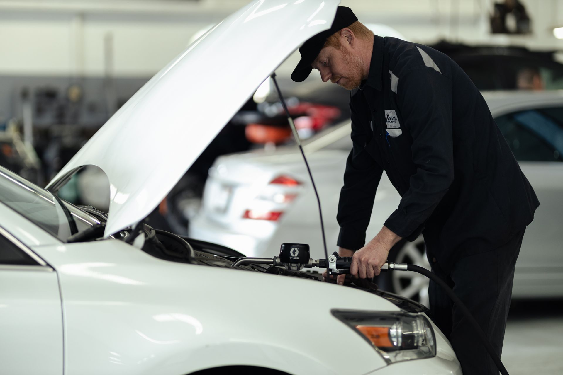 Staff repairing under hood of white vehicle | Larsen Automotive Inc
