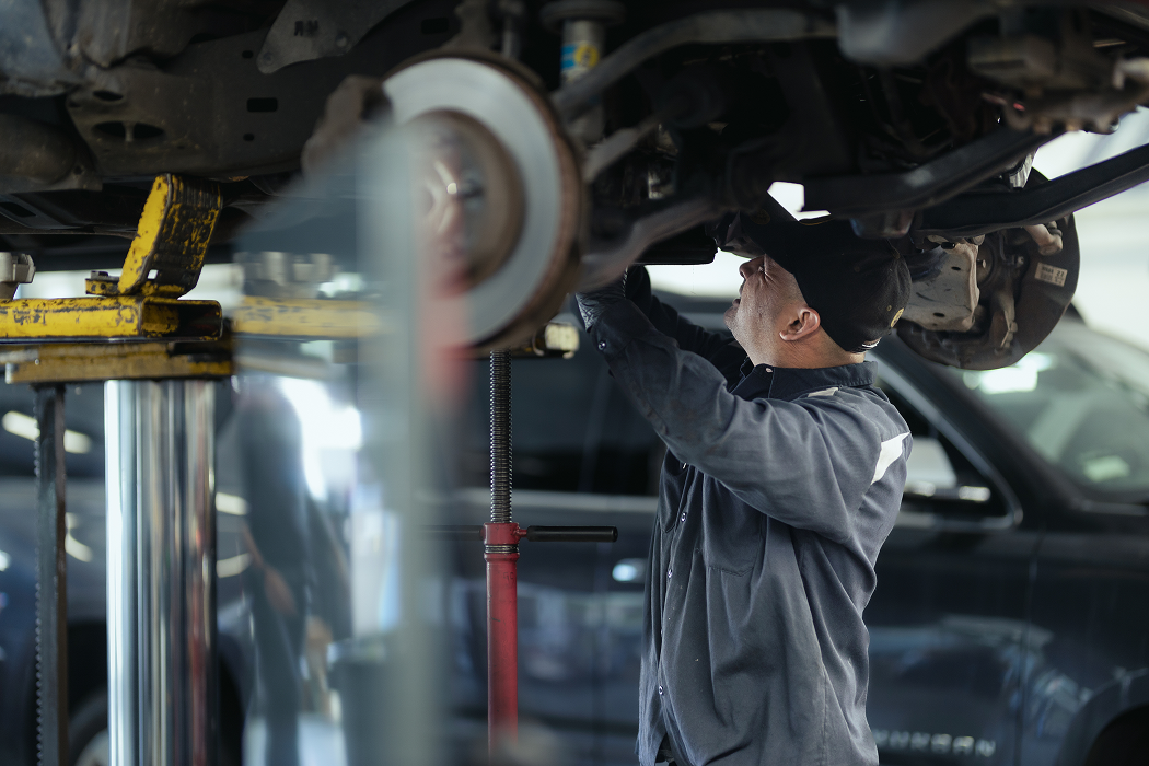 A man is working on the underside of a car in a garage | Larsen Automotive