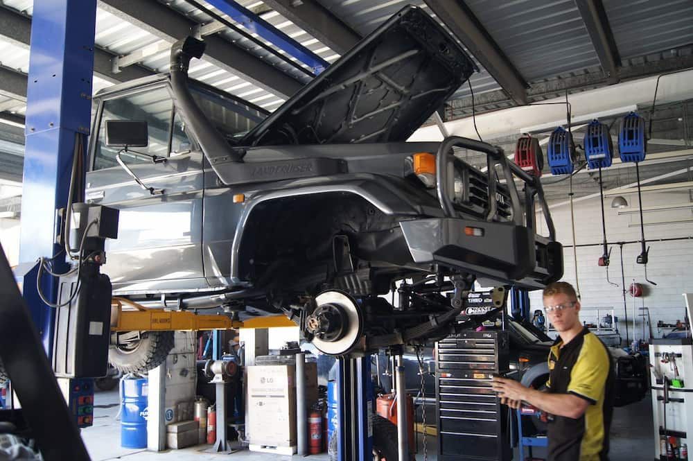 A Man Is Working On A Car In A Garage With The Hood Up — Automotive Repair Centre In Garbutt, QLD