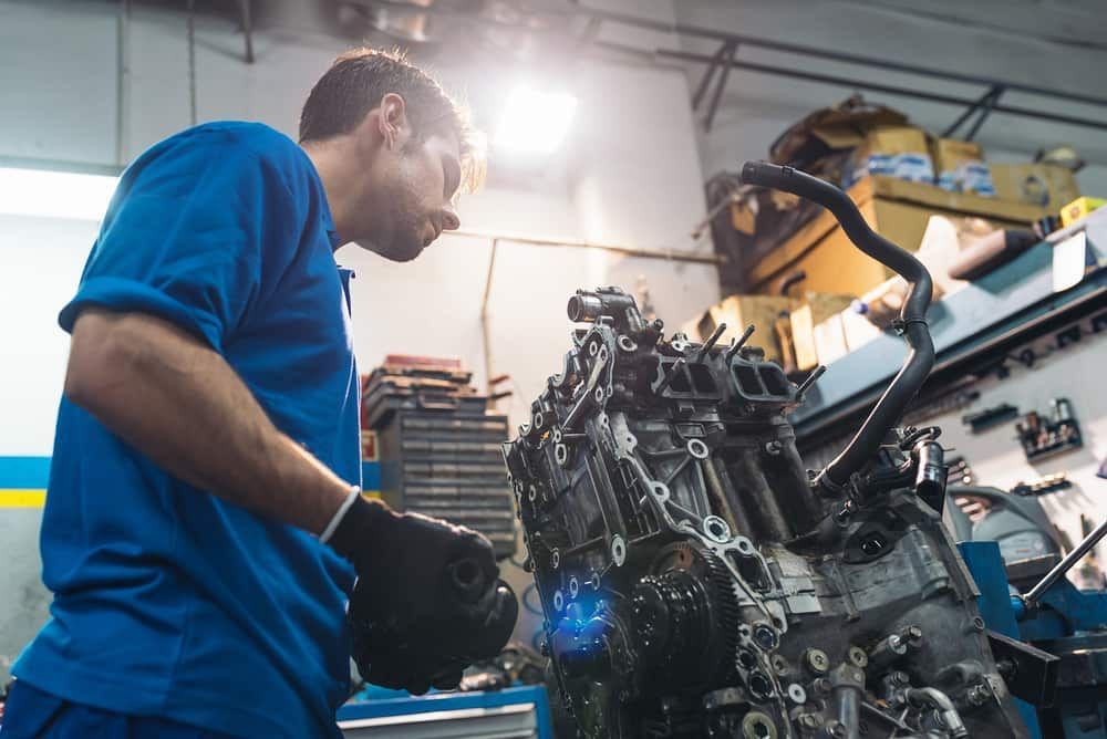 A Man Is Working On A Car Engine In A Garage — Automotive Repair Centre In Garbutt, QLD
