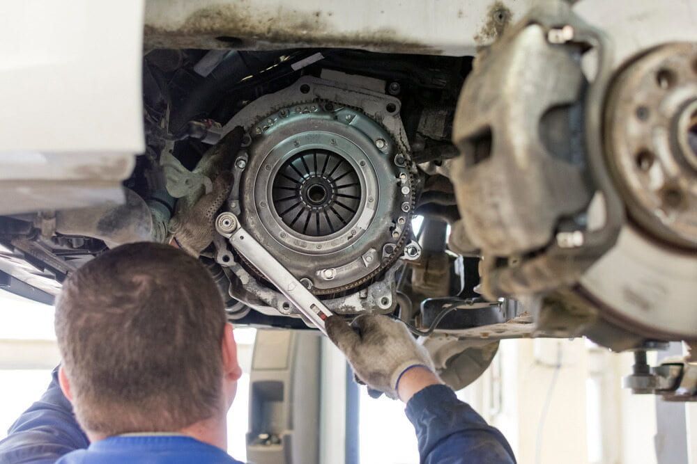 A Man Is Working On A Car Clutch With A Wrench — Automotive Repair Centre In Garbutt, QLD